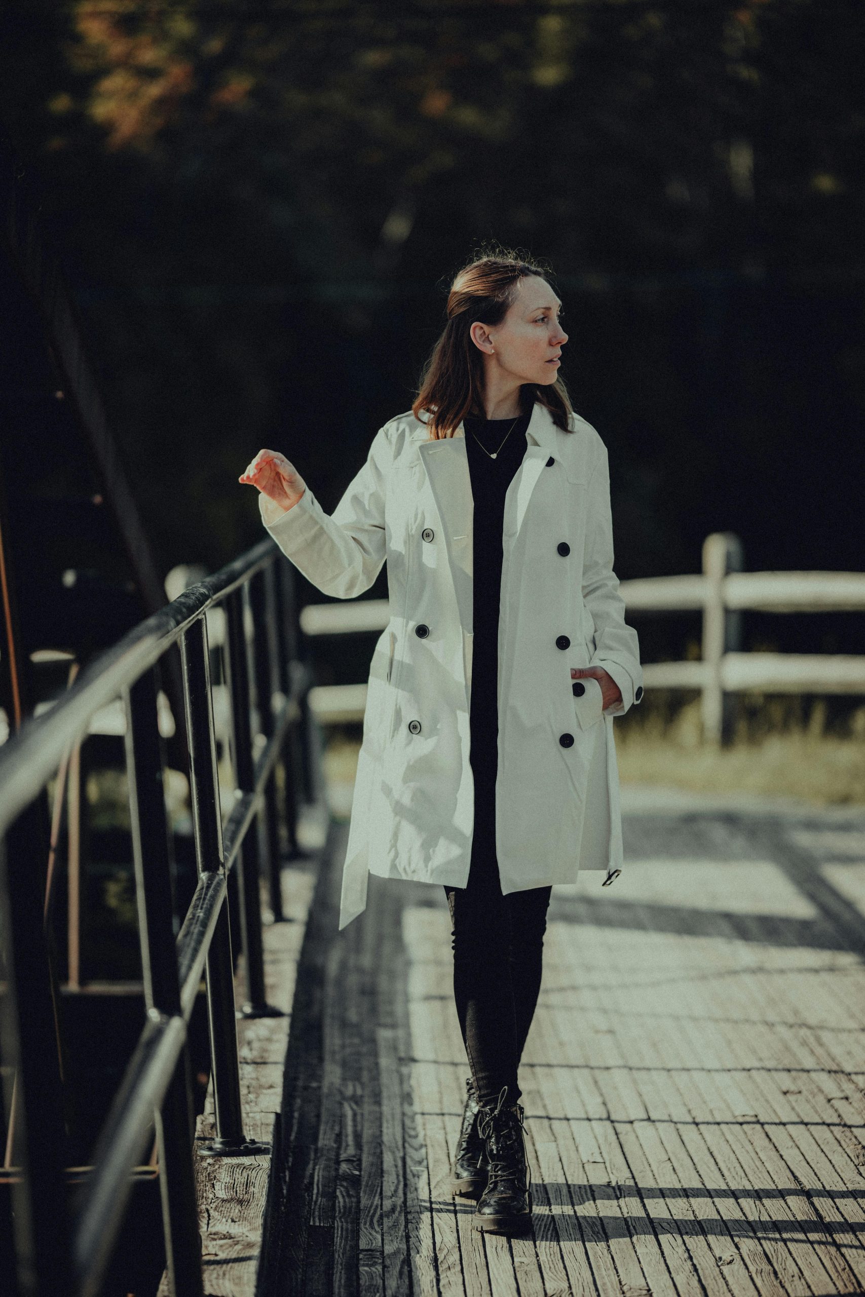 Frau in hellem Mantel geht über eine Brücke – Sinnbild für innere Balance und Klarheit im Berufsleben.