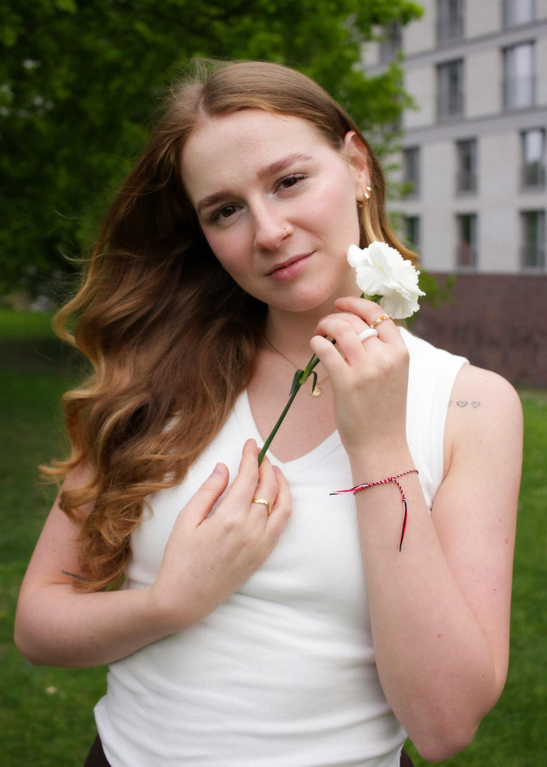Junge Frau mit weißer Blume in ruhiger Natur – Symbol für Vertrauen, emotionale Klarheit und neue Hoffnung