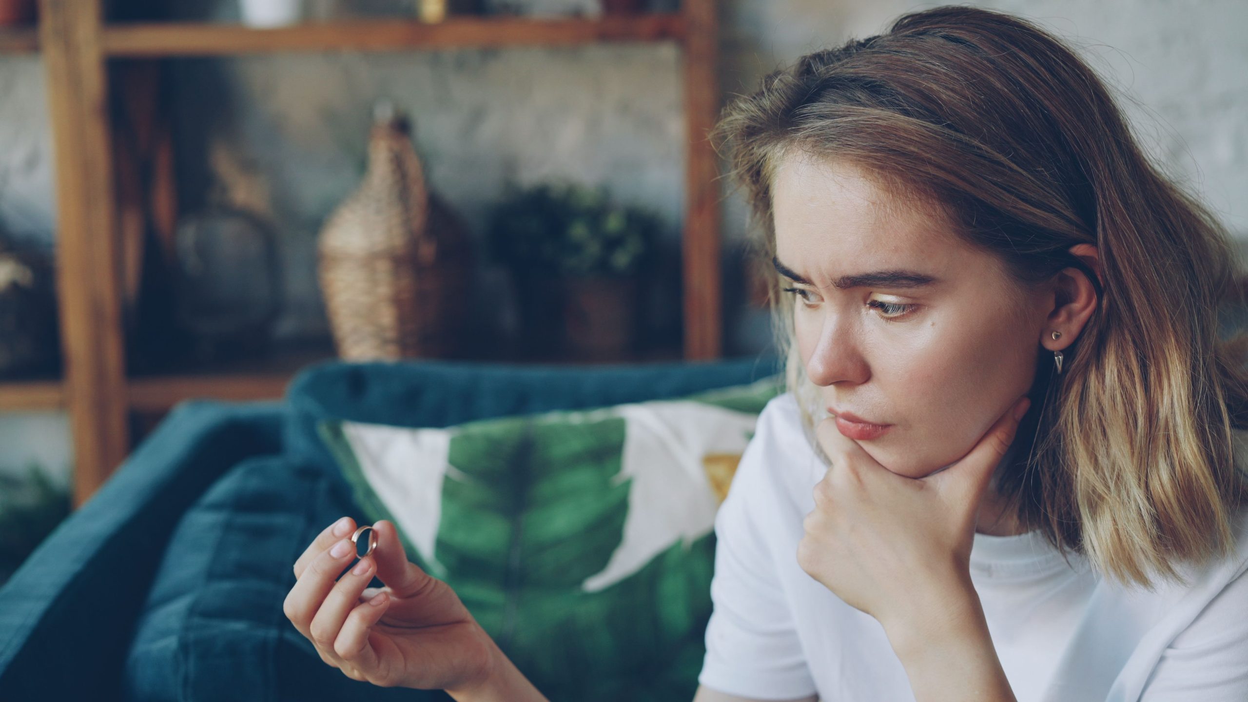 Nachdenkliche Frau mit Ring als Symbol für eine Entscheidung in der Beziehung, Gefühle und die Frage nach einer zweiten Chance
